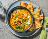 Un invitante pollo al curry cremoso, guarnito con coriandolo fresco e servito con pane naan croccante.