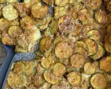 Fette di zucchine al forno dorate e croccanti, condite con parmigiano e pangrattato. Un contorno delizioso e facile da preparare.
