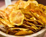Croccanti chips di zucchine dorate, perfette per uno snack sano e gustoso, servite in una ciotola di legno.