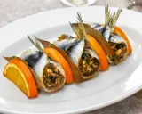 Sarde a beccafico, un piatto siciliano con sardine ripiene, arancia e alloro, servite su un piatto bianco.