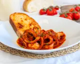 Moscardini in umido, teneri e saporiti, serviti con pane tostato e pomodorini freschi.