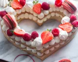 Deliziosa cream tart a forma di cuore per bambini, decorata con fragole, lamponi, meringhe e macarons.