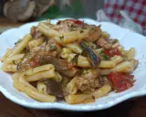 Un piatto invitante di pasta funghi e salsiccia, condita con pomodoro e prezzemolo, pronta per essere gustata.
