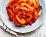 Piatto di peperoni in agrodolce, rossi e gialli, succosi e lucidi, pronti per essere gustati.