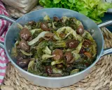 Scarola in padella con olive e uvetta, un contorno saporito e colorato, pronto per essere gustato.