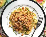 Un piatto invitante di pasta con carciofi alla siciliana, arricchito da ceci e erbe fresche, su un tovagliolo colorato.