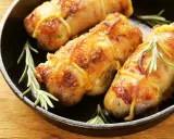 Involtini di pollo in padella, dorati e succulenti, con rametti di rosmarino fresco.