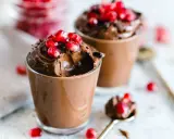 Due bicchierini di golosa mousse al cioccolato, guarniti con chicchi di melagrana e scaglie di cioccolato.