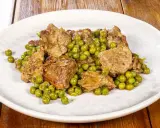 Un saporito agnello con piselli, un classico piatto italiano, servito su un piatto bianco.