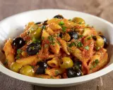 Penne al sugo rosso con olive nere e verdi, capperi e prezzemolo, un piatto di pasta alla puttanesca invitante.