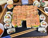 Un invitante sushi fatto in casa con salmone, avocado e formaggio Philadelphia, guarnito con semi di sesamo e una salsa cremosa.