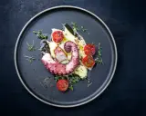 Un tentacolo di polpo alla griglia, servito su purè di patate con pomodorini confit e timo fresco.