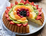 Una deliziosa crostata morbida alla frutta, con fragole, kiwi, mandarini e frutti di bosco su una base soffice e crema.