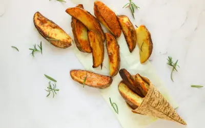 Patate al forno dorate e croccanti, guarnite con rametti di rosmarino fresco. Un piacere per gli occhi e per il palato.