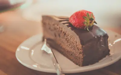 Una fetta di torta al cioccolato, ricoperta di glassa lucida e guarnita con una fragola fresca, pronta per essere gustata.