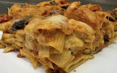 Una fetta di pasta al forno ricca e dorata, con strati di pasta, melanzane e formaggio filante.