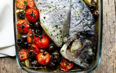 Orata al forno con pomodorini e olive nere, un piatto saporito e profumato, pronto per essere gustato.