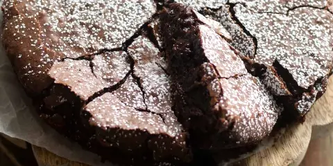 Una deliziosa torta al cioccolato fondente, con una crosta crepata e cosparsa di zucchero a velo, pronta per essere gustata.