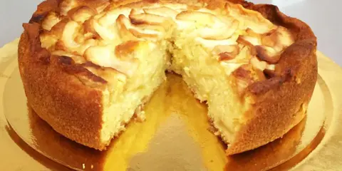 Una deliziosa torta di mele, dorata e soffice, con fette di mela disposte a spirale sulla superficie.