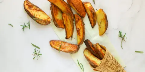 Patate al forno dorate e croccanti, guarnite con rametti di rosmarino fresco. Un piacere per gli occhi e per il palato.