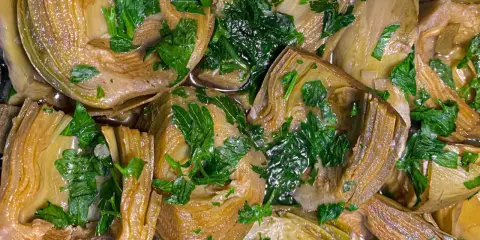Deliziosi carciofi in padella, teneri e profumati, guarniti con prezzemolo fresco. Un piatto semplice e gustoso.