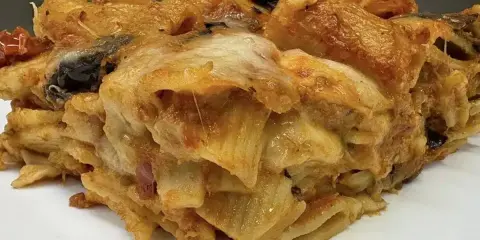 Una fetta di pasta al forno ricca e dorata, con strati di pasta, melanzane e formaggio filante.