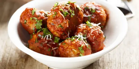 Polpette di carne morbide in salsa rossa, cosparse di parmigiano e prezzemolo fresco.