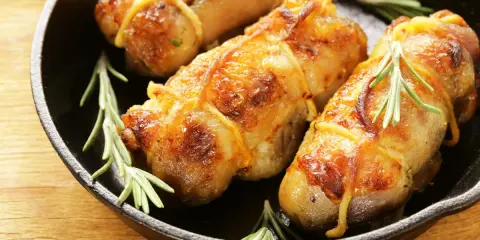 Involtini di pollo in padella, dorati e succulenti, con rametti di rosmarino fresco.