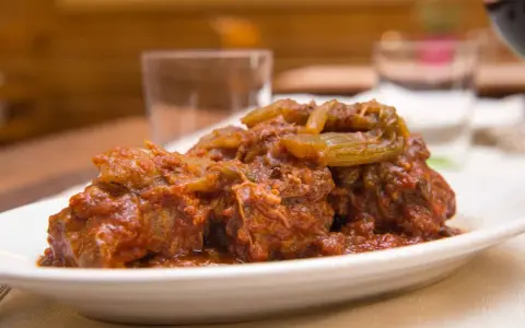 Un succulento piatto di coda alla vaccinara, cotta lentamente in un ricco sugo di pomodoro con verdure.