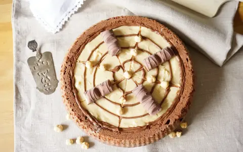 Torta Kinder Bueno con crema chiara, nocciole e decorazioni di cioccolato.