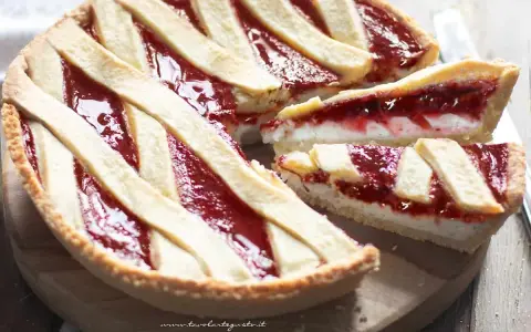 Una deliziosa crostata ricotta e marmellata, con fette tagliate che mostrano il ripieno cremoso e la crosta dorata.