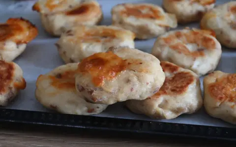 Deliziose polpette di pollo appena sfornate, dorate e con formaggio filante, pronte per essere gustate.