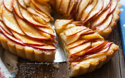 Una fetta di crostata di mele dorata, con mele caramellate disposte a rosa su una base friabile.