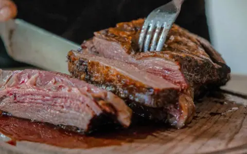 Un succulento arrosto di maiale, tagliato a fette su un tagliere di legno, con una forchetta che affonda nella carne tenera.
