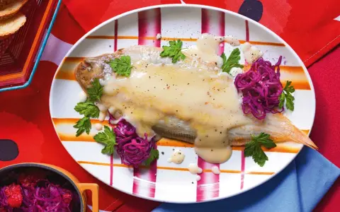 Sogliola alla mugnaia su piatto a righe, guarnita con cavolo rosso e prezzemolo.