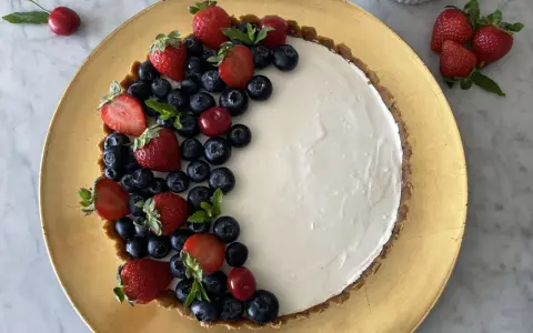 Crostata di frutta fresca con fragole, mirtilli e ciliegie su una base dorata.