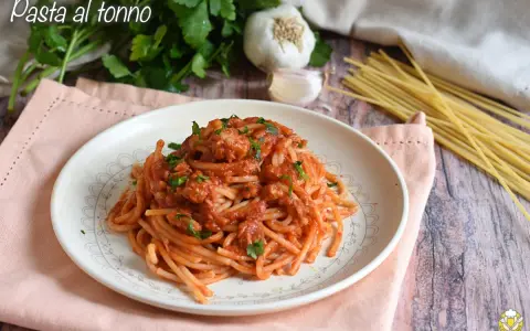 Piatto di spaghetti al sugo con tonno in scatola, guarnito con prezzemolo fresco. Ingredienti per un pasto veloce e gustoso.