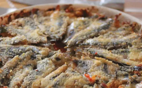 Tortino di alici cotto al forno, con panatura dorata e ingredienti saporiti.