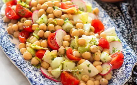Un'appetitosa insalata di ceci con pomodorini, cetrioli e ravanelli, condita con erbe fresche.
