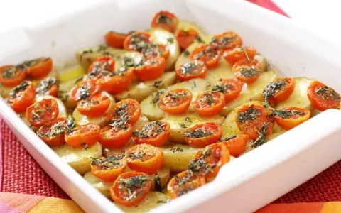 Pomodori gratinati al forno con patate, un piatto semplice e gustoso, pronto per essere infornato.