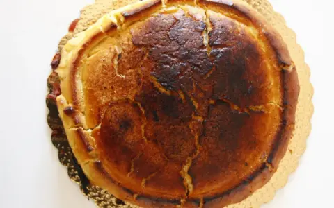 Crostata ricotta e visciole dorata e leggermente bruciacchiata, con un ripieno invitante che traspare dai bordi.