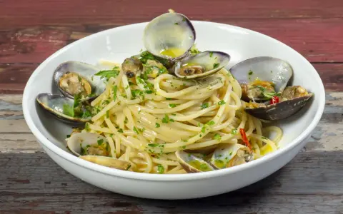 Spaghetti alle vongole surgelate, un piatto gustoso con pasta, vongole e prezzemolo.