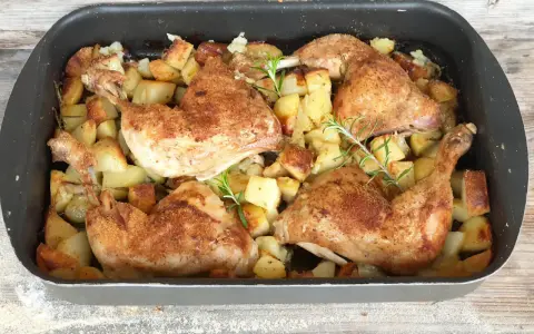 Succulento pollo al forno con patate dorate e rosmarino, pronto per essere gustato.