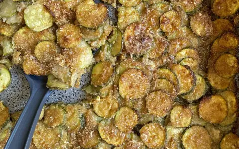 Fette di zucchine al forno dorate e croccanti, condite con parmigiano e pangrattato. Un contorno delizioso e facile da preparare.