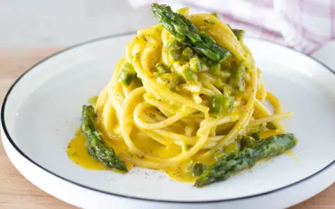 Spaghetti cremosi con asparagi, una deliziosa carbonara di asparagi, guarnita con punte verdi croccanti.