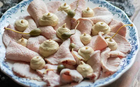 Vitello tonnato ricetta originale piemontese: fettine sottili di carne rosa, guarnite con salsa tonnata e capperi.