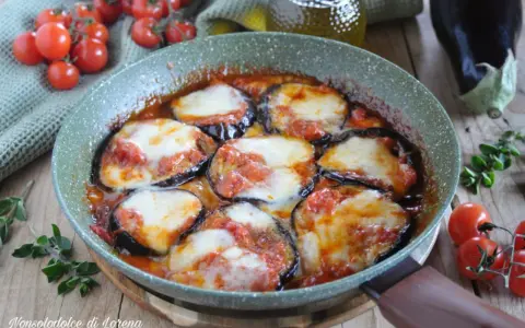 Melanzane alla pizzaiola in padella, con pomodoro e mozzarella filante, contornate da pomodorini freschi e basilico.