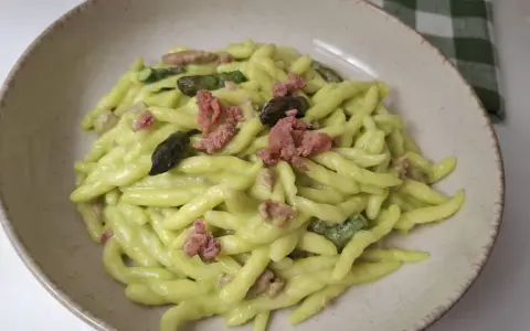 Piatto di pasta fresca con crema di asparagi, pezzetti di salsiccia e punte di asparagi.