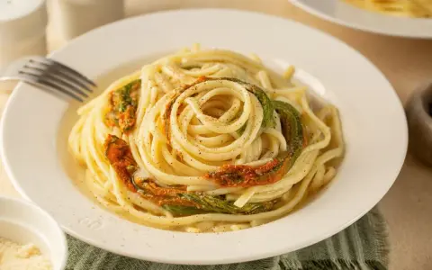 Un piatto di spaghetti conditi con delicati fiori di zucca, un classico della cucina italiana.