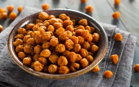 Ceci croccanti al forno, uno snack salutare e gustoso, serviti in una ciotola su un tovagliolo di lino.